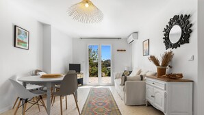 Ein modernes Wohnzimmer mit Essbereich, einer Couch, einem Couchtisch, einem Fernseher und einem dekorativen Spiegel.