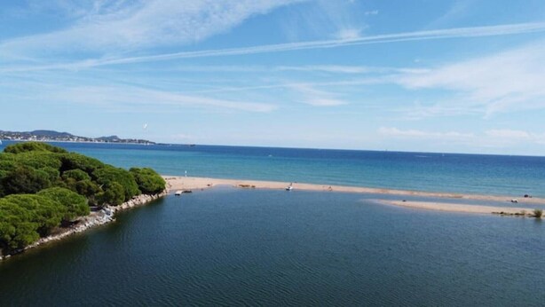 Eine Küstenlandschaft mit Strand, ruhiger See und dichter Vegetation.