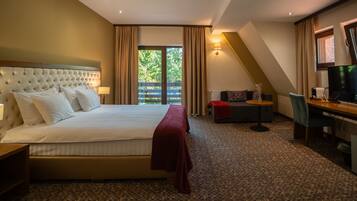 A hotel room with a large bed, a desk, a chair, and a TV.