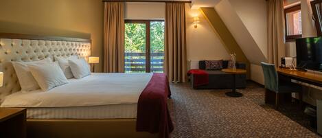Une chambre d’hôtel avec un grand lit, un bureau, une chaise et un téléviseur.
