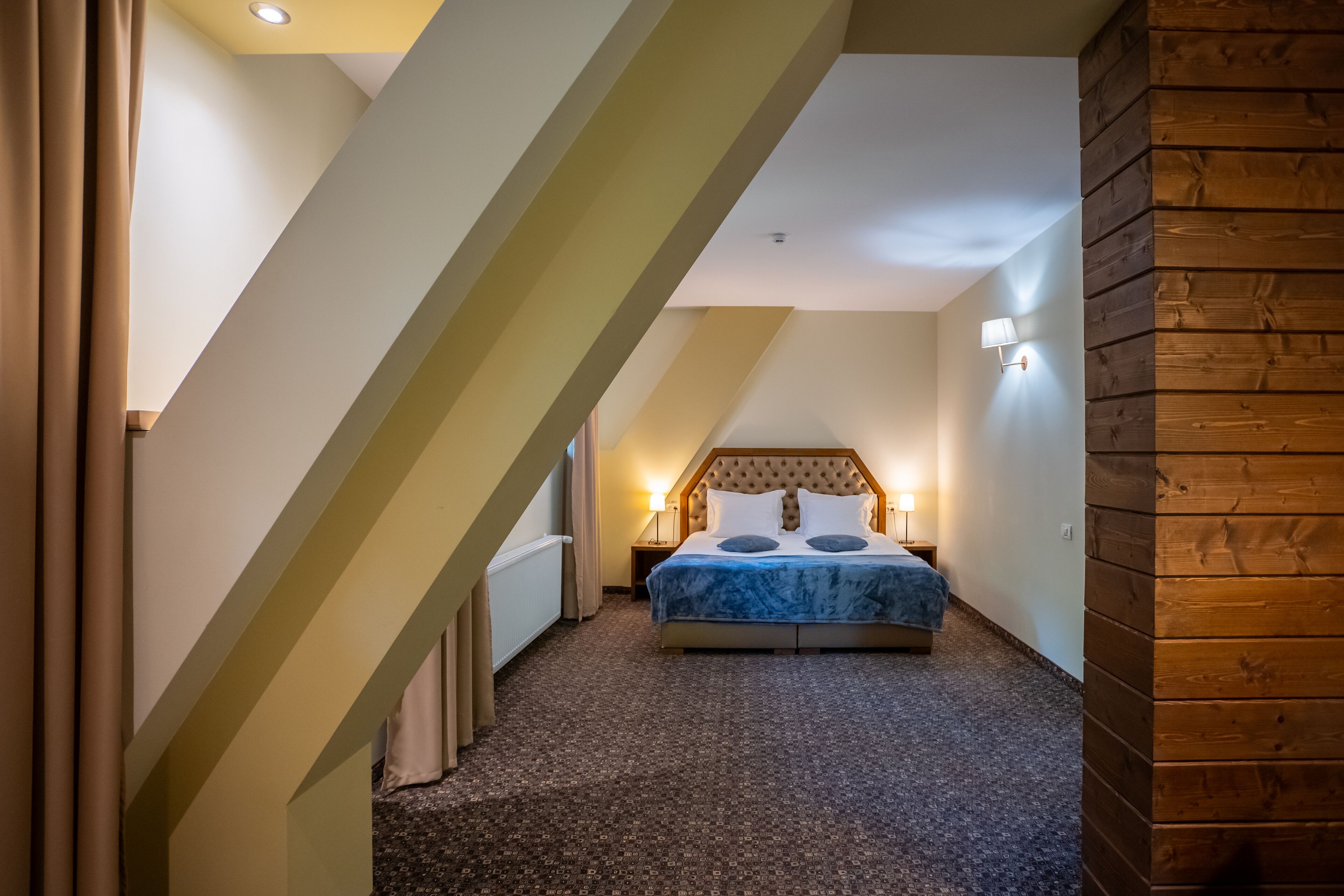 A bedroom with a bed, a nightstand, and a wall-mounted lamp.