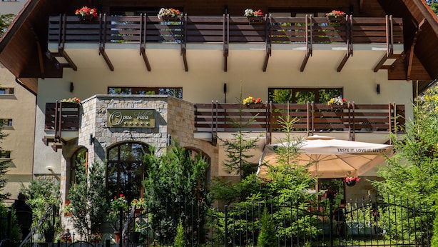 A hotel with a stone facade, wooden balconies with flower boxes, and a clear sky. - Opus Villa (Sinaia)