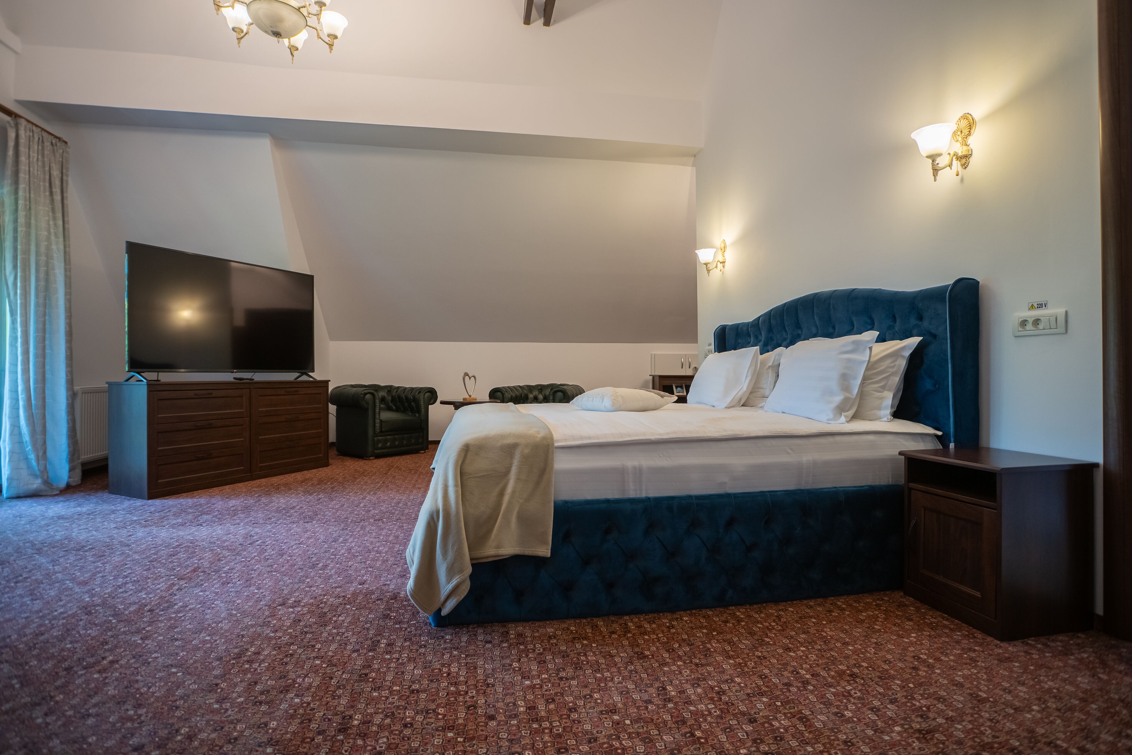 Een slaapkamer met een groot bed, een flatscreen-tv, een dressoir en een nachtkastje.