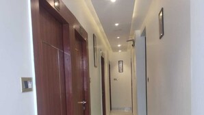 Un pasillo con suelo de mármol, puertas de madera e iluminación empotrada.