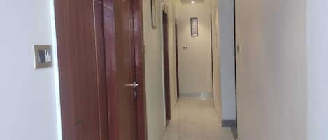 A hallway with marble flooring, wooden doors, and recessed lighting.