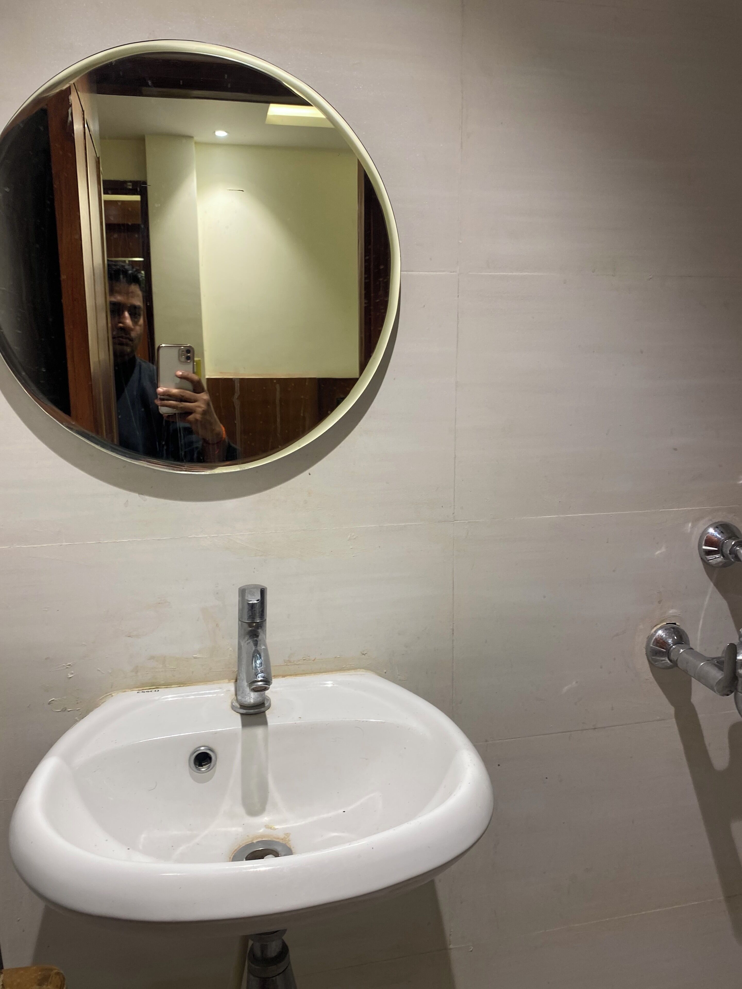 A bathroom with a white sink, a round mirror, and a visible door.