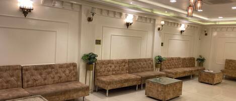 A spacious lobby with a modern design, featuring a large seating area with sofas and a glass coffee table.