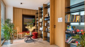 Ein modernes Interieur mit Holzregalen, einem Essbereich mit einem roten Sessel und einem Blumentopf.