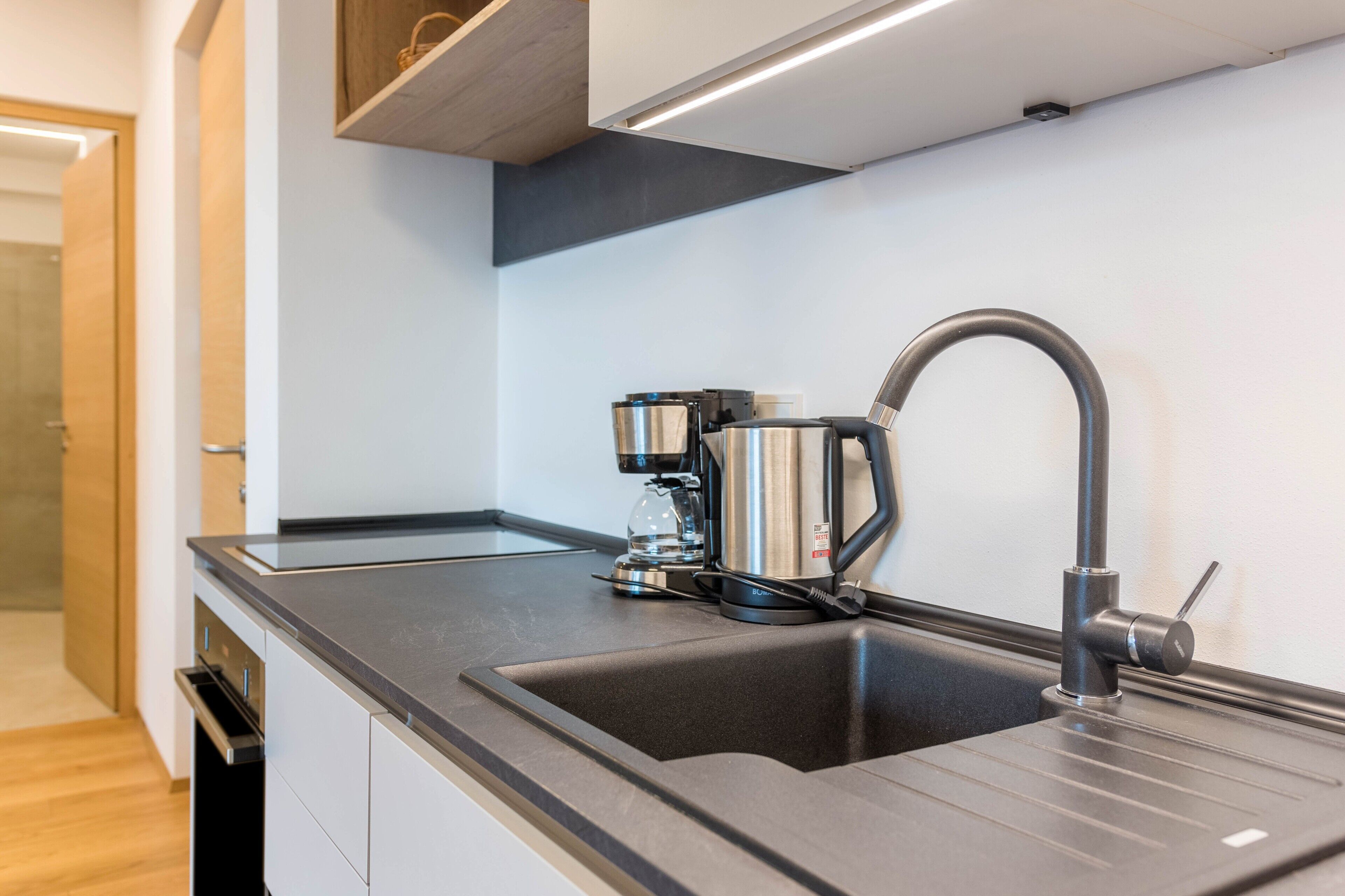 A modern kitchen with a stainless steel sink, a coffee machine, and a sleek faucet.