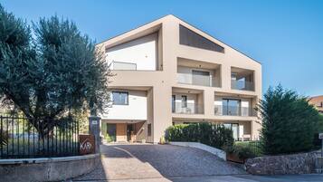 Un immeuble moderne à plusieurs étages, doté d’un toit plat, de balcons et d’un espace d’entrée pavé.