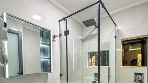 Une salle de bain moderne avec une douche à parois de verre, un lavabo blanc et un miroir au-dessus.