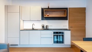 A modern kitchen with white cabinetry, a built-in oven, and a wooden shelf above the counter. - Holiday Apartment "Karin - Cabernet" with Shared Terrace and Wi-Fi (Termeno)