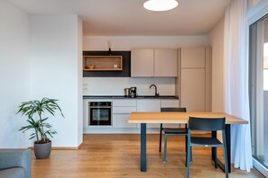 A modern kitchen with a dining area, a potted plant, and a view through a window. - Apartment "Karin - Lagrein" with Shared Terrace & Wi-Fi (Termeno)