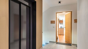 Corredor com porta moderna, uma placa indicando um quarto e um vislumbre de uma cozinha.