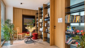Un intérieur moderne avec des étagères en bois, un coin repas agrémenté d’une chaise rouge et une plante en pot.