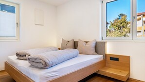 Une chambre moderne avec un lit, une fenêtre et une vue sur des immeubles.