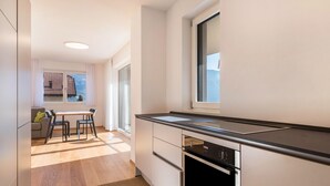 A modern kitchen with a black countertop, white cabinets, and a window with a view of a building. - Apartment "Karin - Golden" with Shared Terrace and Wi-Fi (Termeno)