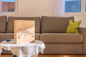 Un classeur en bois avec du texte, posé sur une table devant un canapé sur lequel se trouve un coussin vert.
