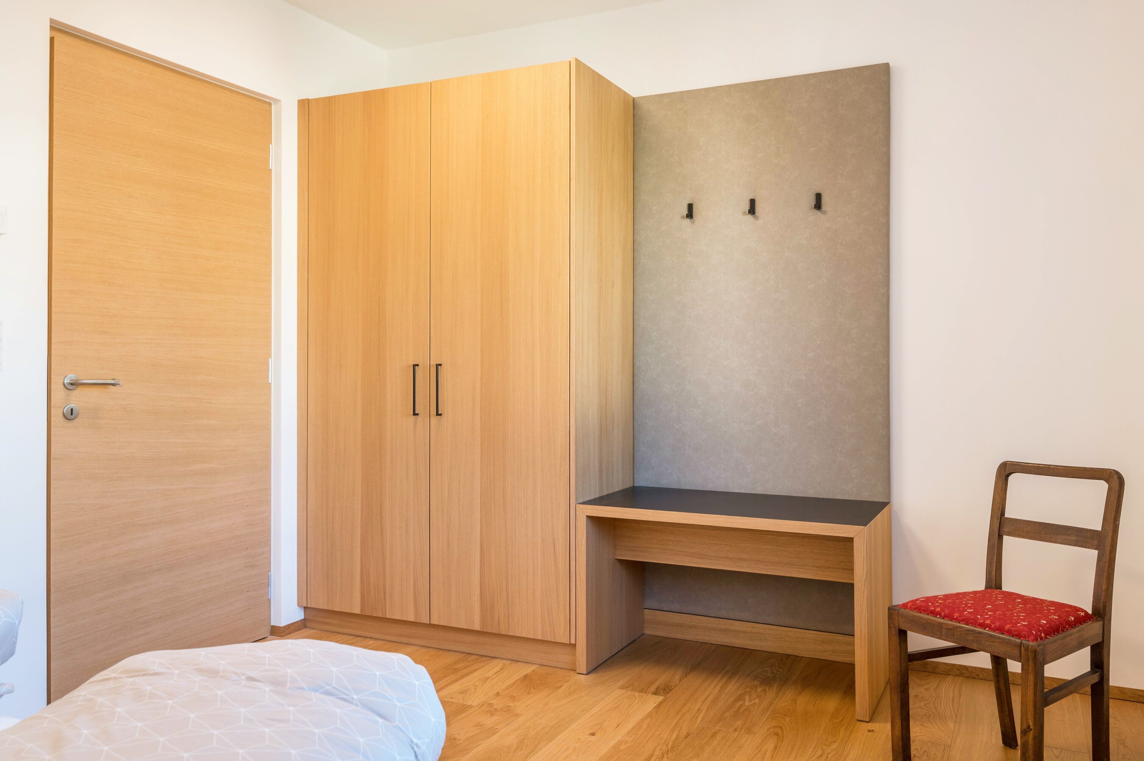 Un dormitorio con un armario de madera, un escritorio y una silla.