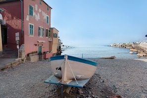 A boat on a pebbled shore with buildings in the background.