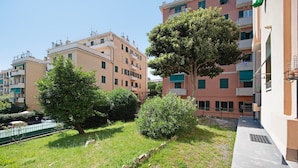 A residential area with apartment buildings, a grassy courtyard, and a tree.
