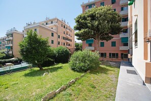 A residential area with apartment buildings, a grassy courtyard, and a tree.