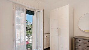 A bedroom with a bed, a wardrobe, a dresser, and a sliding glass door leading to a balcony.