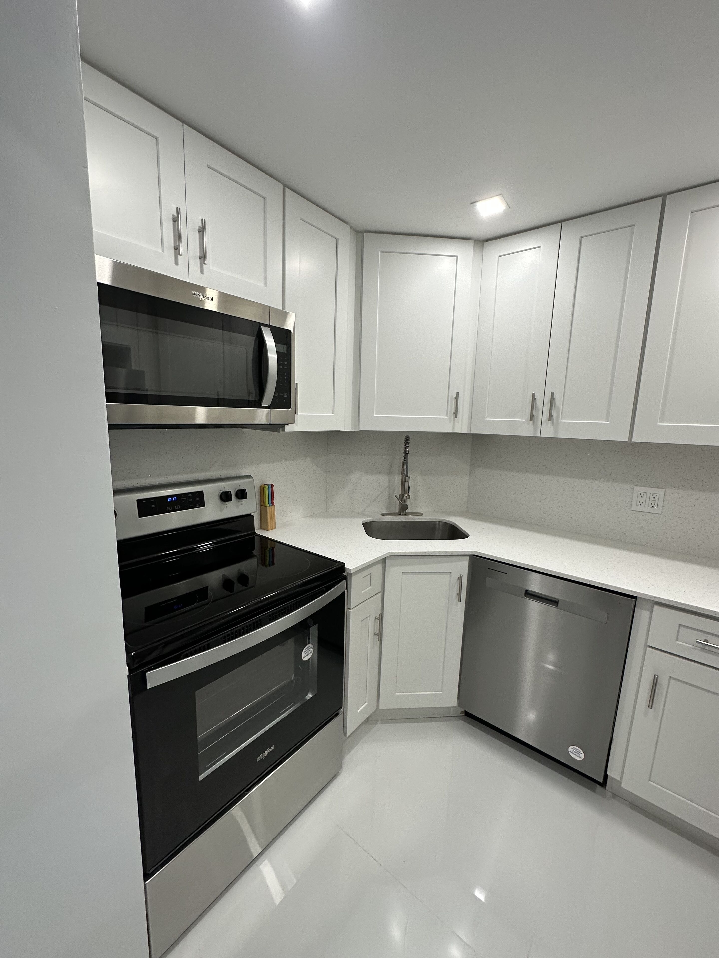A modern kitchen with white cabinets, stainless steel appliances, and a white countertop.
