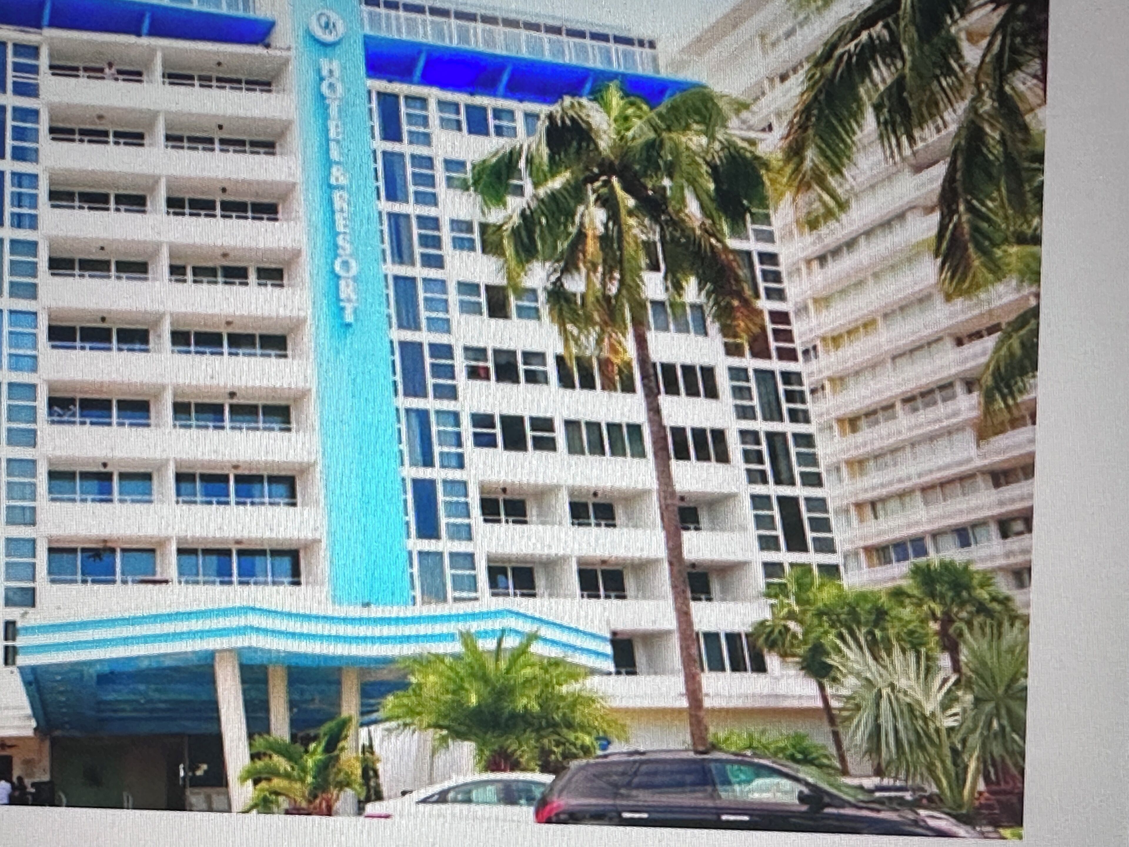 Un hôtel à plusieurs étages, doté d’une façade bleue et blanche remarquable, et d’une enseigne verticale centrale portant le nom de l’hôtel.