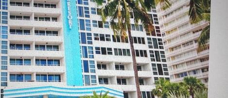 Un hôtel à plusieurs étages, doté d’une façade bleue et blanche remarquable, et d’une enseigne verticale centrale portant le nom de l’hôtel.