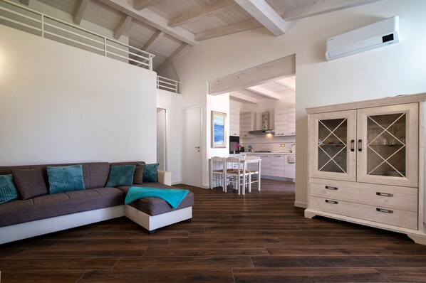 A modern living room with a sofa, a cabinet, and a dining area.