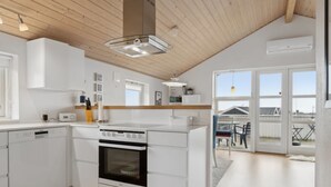 A modern kitchen with white cabinetry, a built-in oven, and a large window overlooking a balcony.