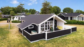 A modern house with a large porch, a covered outdoor seating area, and a well-maintained lawn.