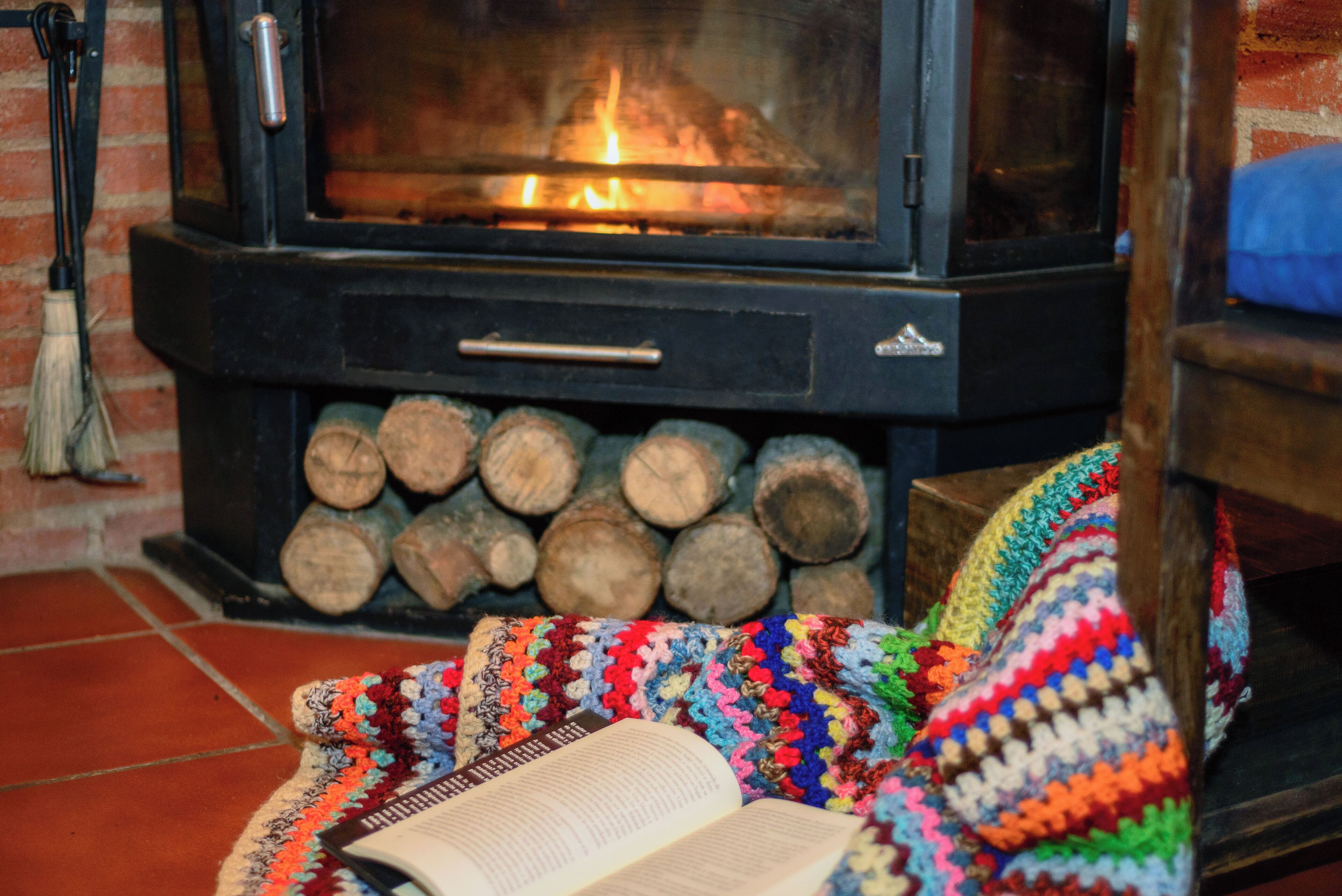 A cozy room with a fireplace, a bookshelf, and a colorful blanket.