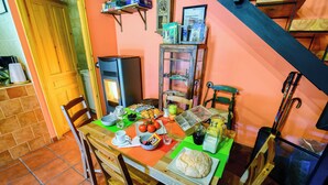 A dining area with a wooden table, chairs, and a variety of food items. - Casa Rural en la Montaña de León. Entre Valles (Benllera)