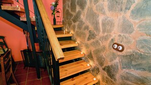 A wooden staircase with built-in lighting, leading to a stone wall. - Casa Rural en la Montaña de León. Entre Valles (Benllera)