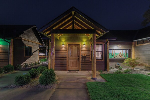 A wooden house with a covered porch, a front door, and a small garden.