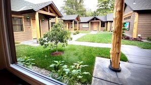 On voit une rangée de cabanes en bois, avec une pelouse verdoyante et un petit arbre au premier plan.