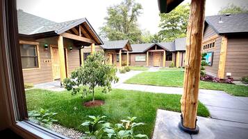 A view of a row of wooden cabins with a grassy lawn and a small tree in the foreground.