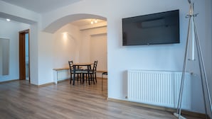 Una habitación amplia con comedor, televisor montado y radiador.