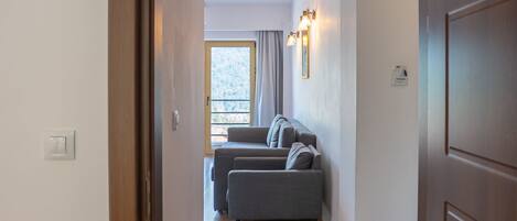 A hallway leading to a living area with a sofa and a window.