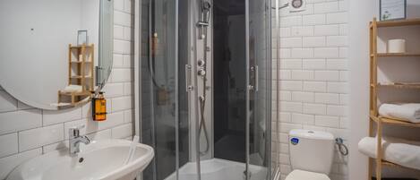 A modern bathroom with a glass-enclosed shower, a sink, and a toilet.