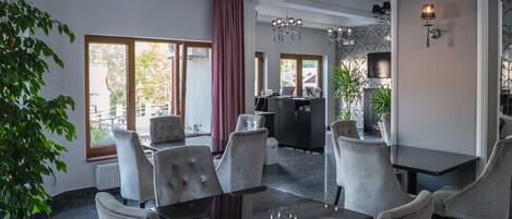 Un comedor moderno con una mesa redonda, sillas acolchadas y una araña.