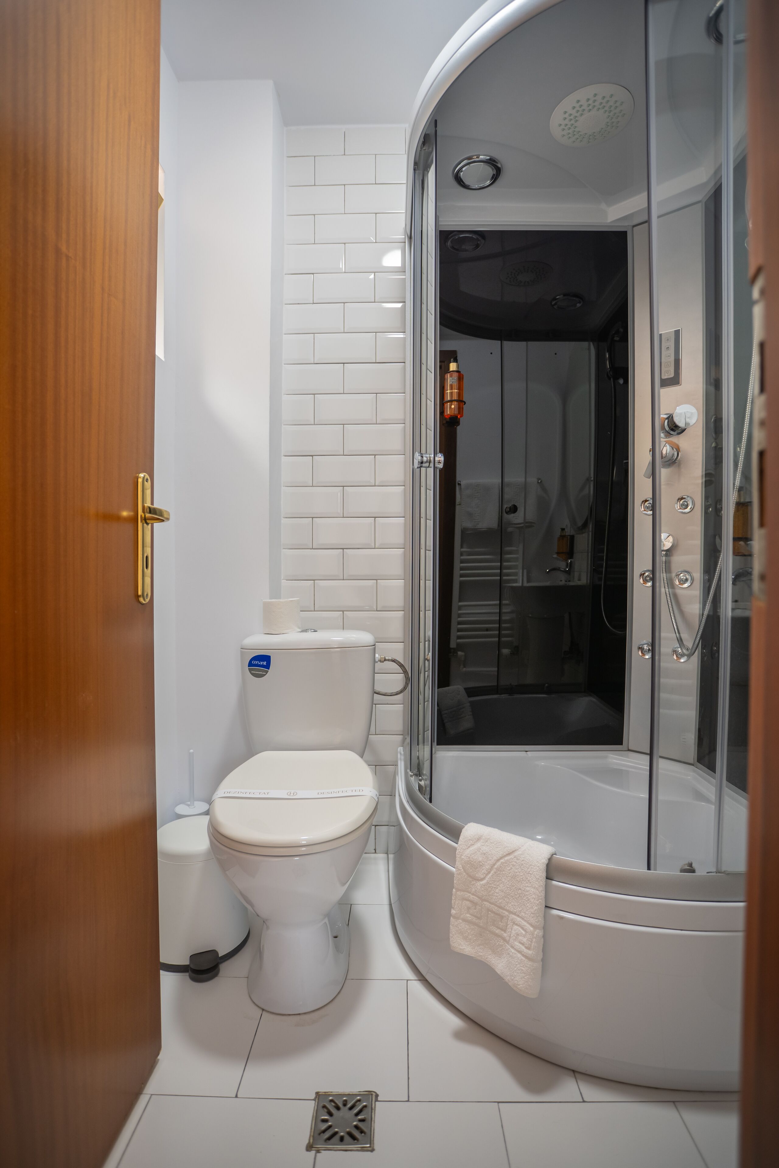 Ein modernes Badezimmer mit Toilette, einer gläsernen Dusche und einer weiß gefliesten Wand.