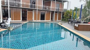 A rectangular pool with blue tiles, surrounded by a wooden deck and outdoor seating. - Hi Creek Resort  (Si Bun Rueang)