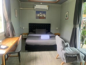 A bedroom with a bed, bedside tables, a desk, a chair, an air conditioning unit, and a window with curtains. - Hi Creek Resort  (Si Bun Rueang)