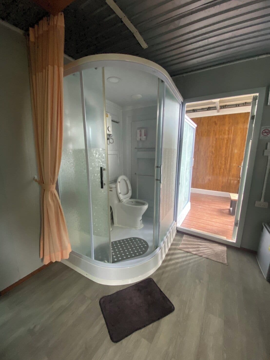 A bathroom with a glass enclosure, a toilet, and a shower area.