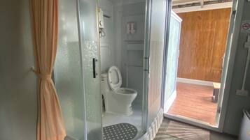 A bathroom with a glass enclosure, a toilet, and a shower area.