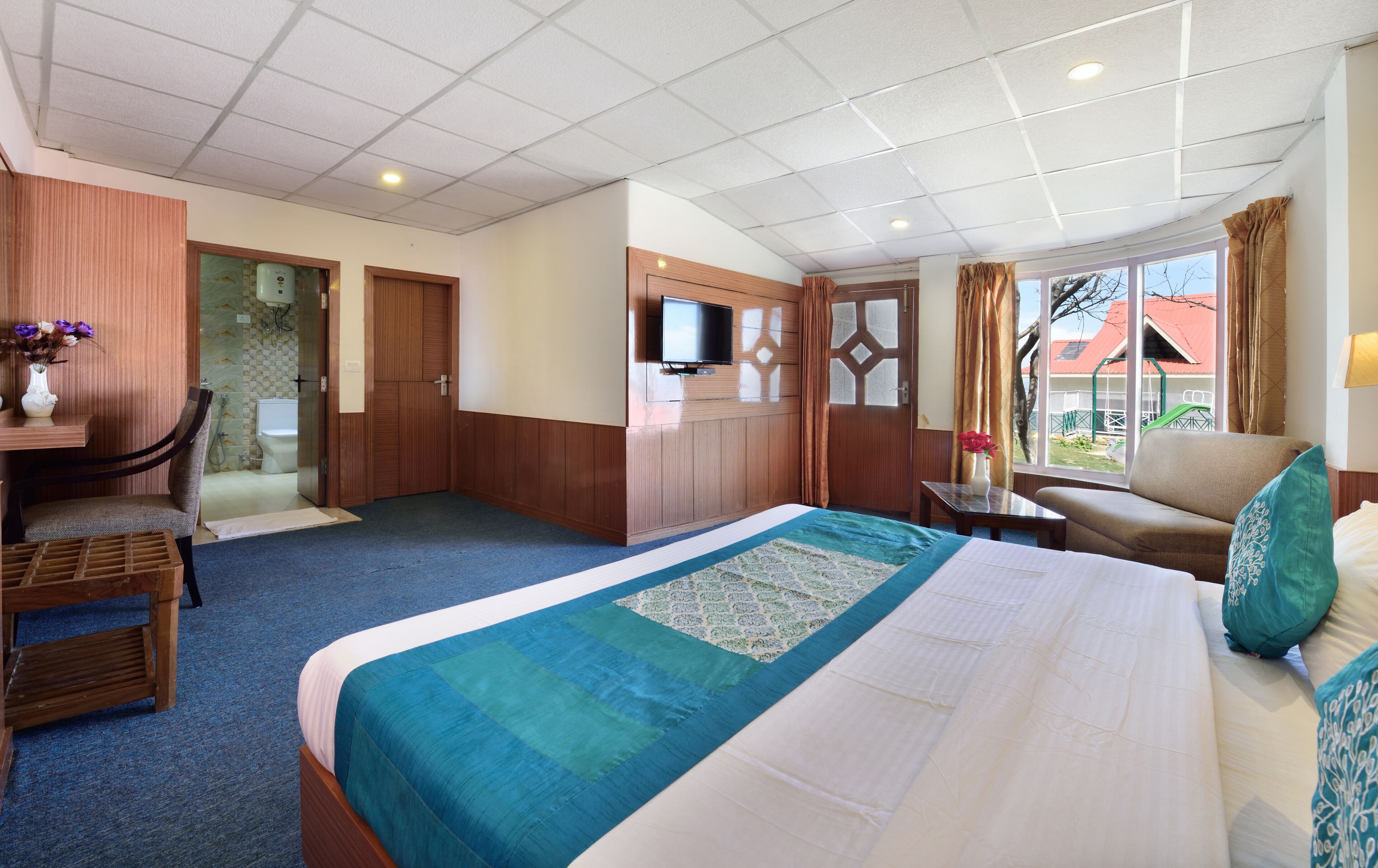 A hotel room with a bed, a desk, a chair, a television, and a window with a view of the outside.