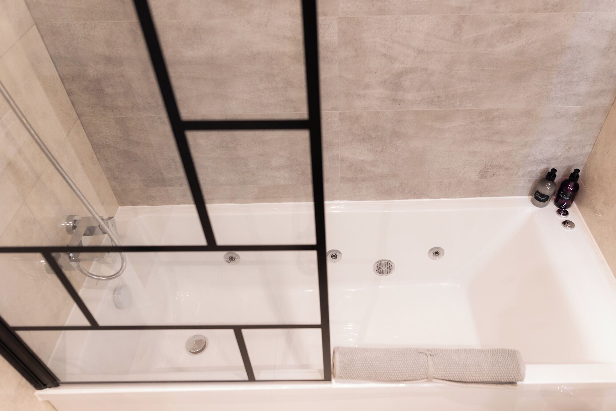 Un baño moderno con cabina de ducha de vidrio, bañera y barra para toallas.